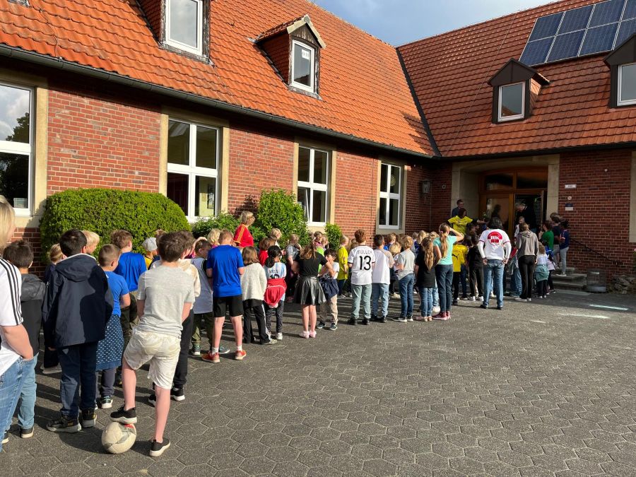 Ein Spalier vvon jubelnden Kindern und Kollegen empfängt H.Schiffbauer