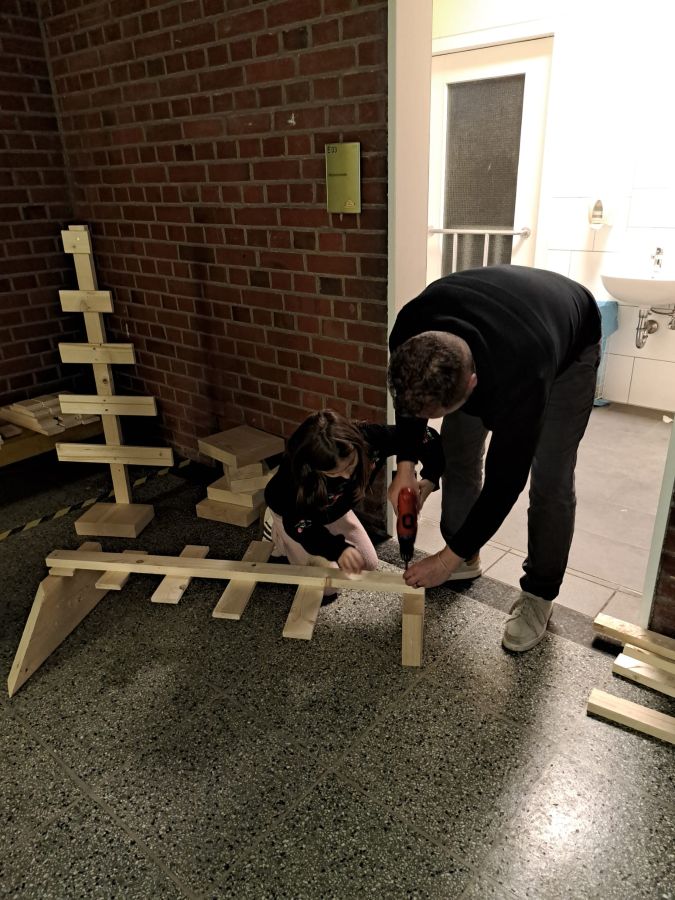 Mittatkräftiger Unterstützung von Elektroschraubern und Eltern entstehen Tannenbäume aus Holzlatten.